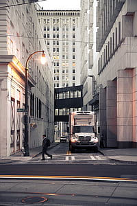 man crossing road near white truck during daytime thumbnail