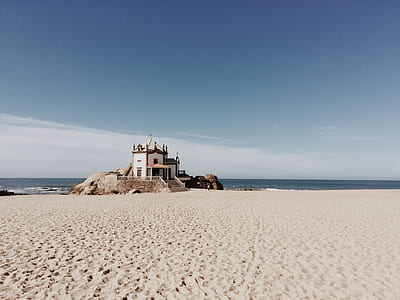 white and brown concrete house near sea under blue sky at daytime thumbnail