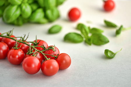 red tomatoes on white surface beside green leaves thumbnail