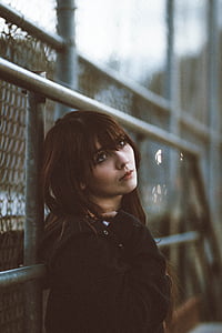 woman leaning on chain link fence looking up thumbnail
