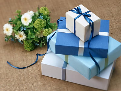 stack of four assorted-color gift boxes beside white and green petaled flower bouquet thumbnail