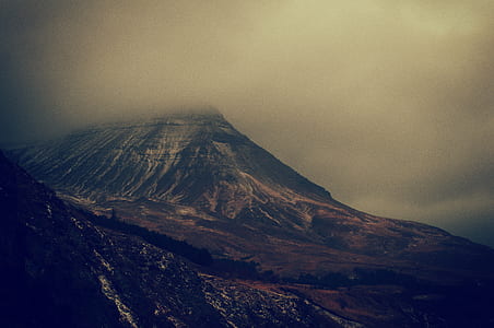 mountain surrounded with fogs under gray cloudy sky thumbnail