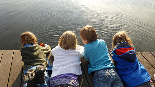 four children proning on brown harbor dock at daytime thumbnail