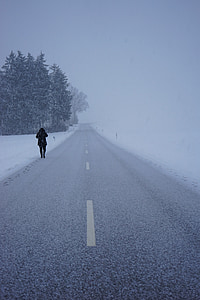 person walking beside gray road during snow thumbnail