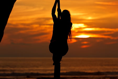 silhouette of woman on pole bar near body of water thumbnail