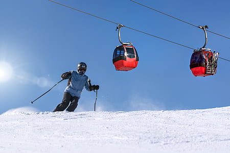 person skiing on snow under cable cart under blue sky thumbnail