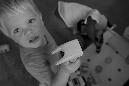 Greyscale Photo of Boy on Tshirt Holding Brown Wood thumbnail