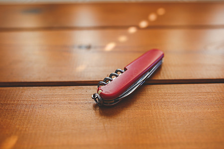 red multi-function tool on brown wooden surface thumbnail