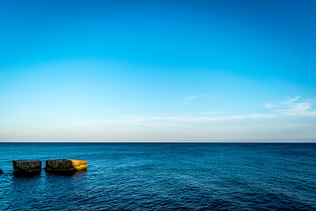 landscape photography of sea and two boulders during daytime thumbnail