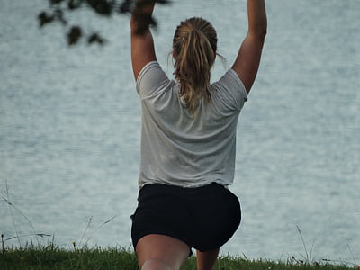 woman raising both hands upwards near body of water thumbnail