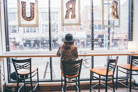 Woman wearing a hat sitting at a window in the city thumbnail