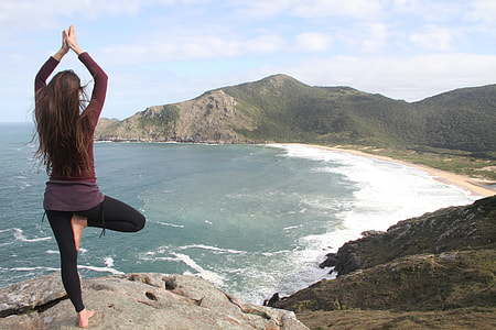 woman making yoga position standing on gray rock mountain during daytime thumbnail
