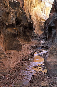Close Up Photo of Black Rock Formation With Litter Amount of River in the Middle of Valley thumbnail