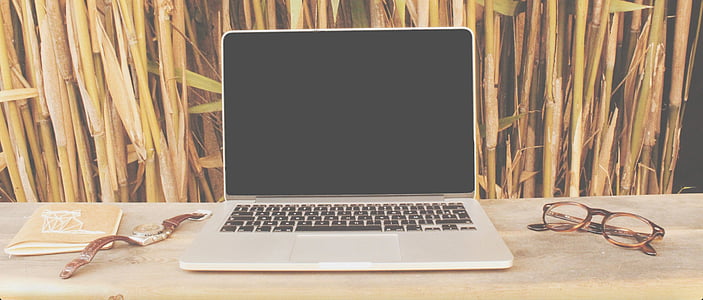 MacBook near eyeglasses and watch on desk thumbnail
