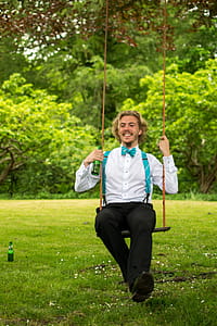 Man in White Dress Shirt and Black Pants Sitting on Swing thumbnail