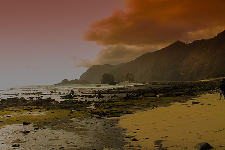 dim clouds approaching above rocky seashore near mountain thumbnail