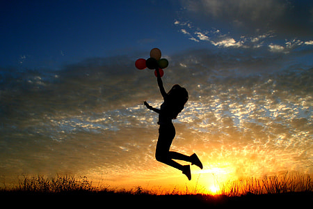 silhouette woman holding balloons photo during sunset thumbnail