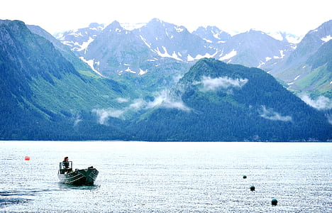 boat on calm body of water next to mountains thumbnail
