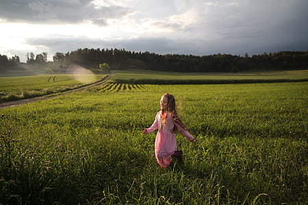 Girl Running on Green Grass Field Near Open Road thumbnail