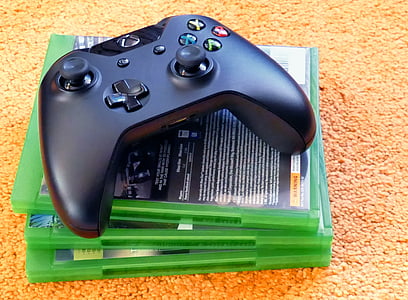 black Microsoft Xbox One controller on three Xbox One game cases thumbnail