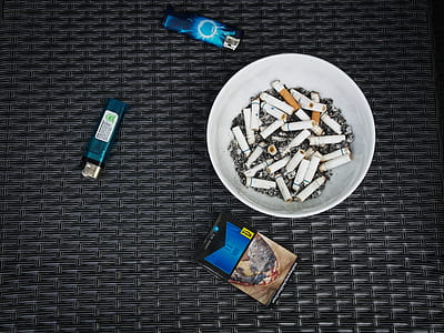 blue and black flip-top cigarette box besides ceramic ashray thumbnail