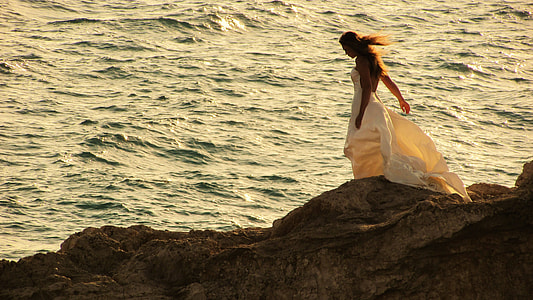 women's wearing white wedding gown near body of water during day time thumbnail