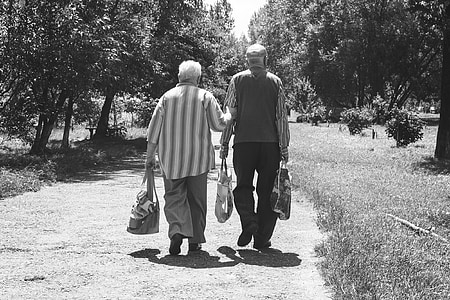 grayscale photo of man and woman walking on dirt road thumbnail