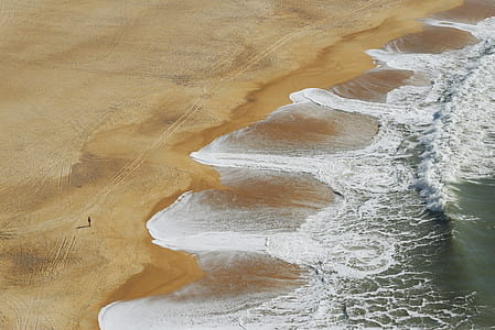 bird's eye view of person standing on seashore while looking at splashing waves thumbnail