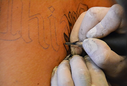 person holding ink draws tattoo thumbnail