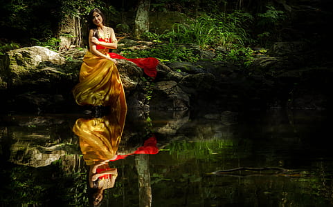 mirror photography of woman in orange and red dress in forest thumbnail
