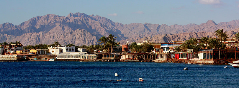 photo of buildings near near with a view of mountain during daytime thumbnail