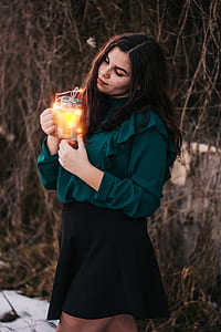woman holding yellow LED light near brown branches during daytime thumbnail