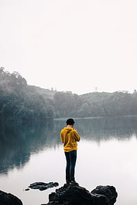person standing on stone beside body of water during daytime thumbnail