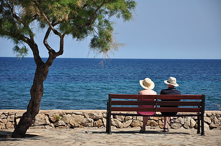 two person sitting on brown wooden pallet bench facing sea thumbnail
