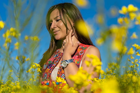 Woman Wearing Gray Watch Standing on a Bed of Yellow Flowers thumbnail