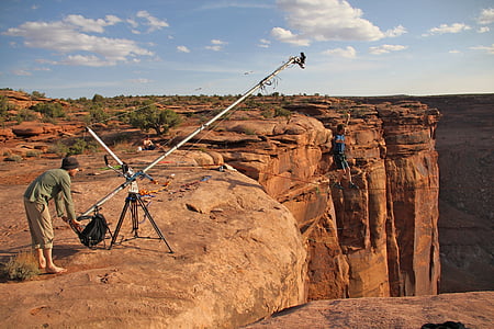 person walking on black rope near the brown cliff at daytime thumbnail