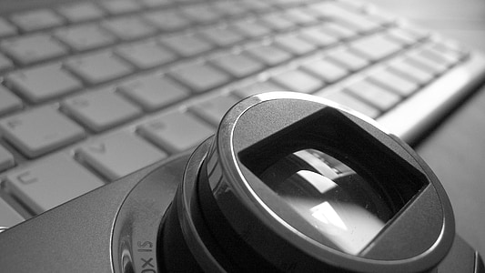 grayscale photo of compact camera beside laptop computer thumbnail