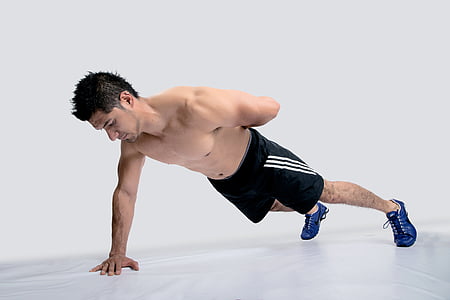 man wearing black Adidas shorts and blue shoes executing push-up with one hand thumbnail