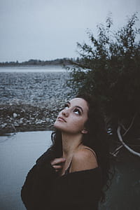 woman wearing black fur top near plant and body of water thumbnail