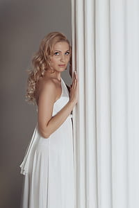 woman wearing white one-strap dress standing infront of white wall inside room thumbnail