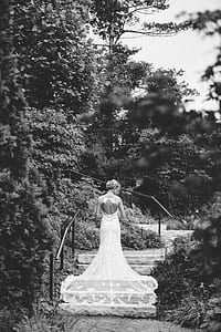 grayscale photo of woman standing on stairs surrounded with trees thumbnail