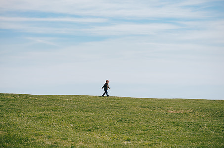 person walking on green grass field photo thumbnail