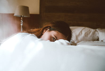 woman lying on bed covered in blanket thumbnail