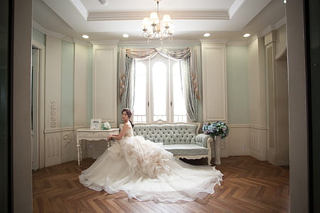 woman wearing white wedding gown sitting on sofa near window thumbnail