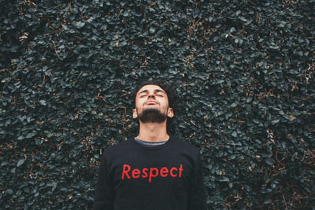 man in black and red top standing near grass wall thumbnail