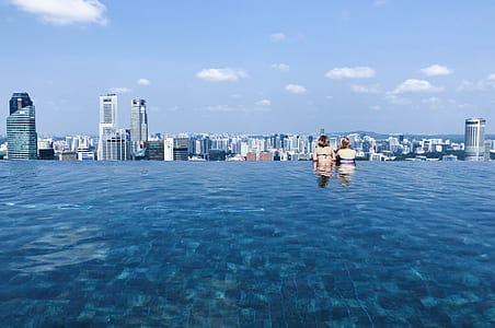 two woman in swimming pool overlooking city view thumbnail