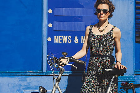 woman in black and white sleeveless dress holding grey bike thumbnail