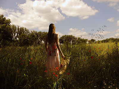 woman in white and pink dress in green fields under white and blue sky thumbnail
