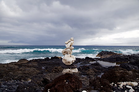 stack of white stones on black surface in front ocean thumbnail