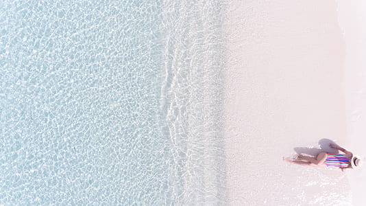 aerial photography of woman lying on seashore thumbnail
